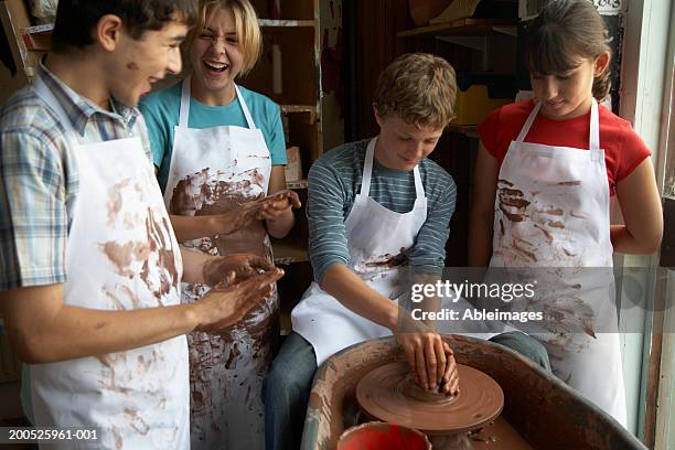 boy (13-15) potting on wheel surrounded by classmates - 12 year old blonde girl stock pictures, royalty-free photos & images