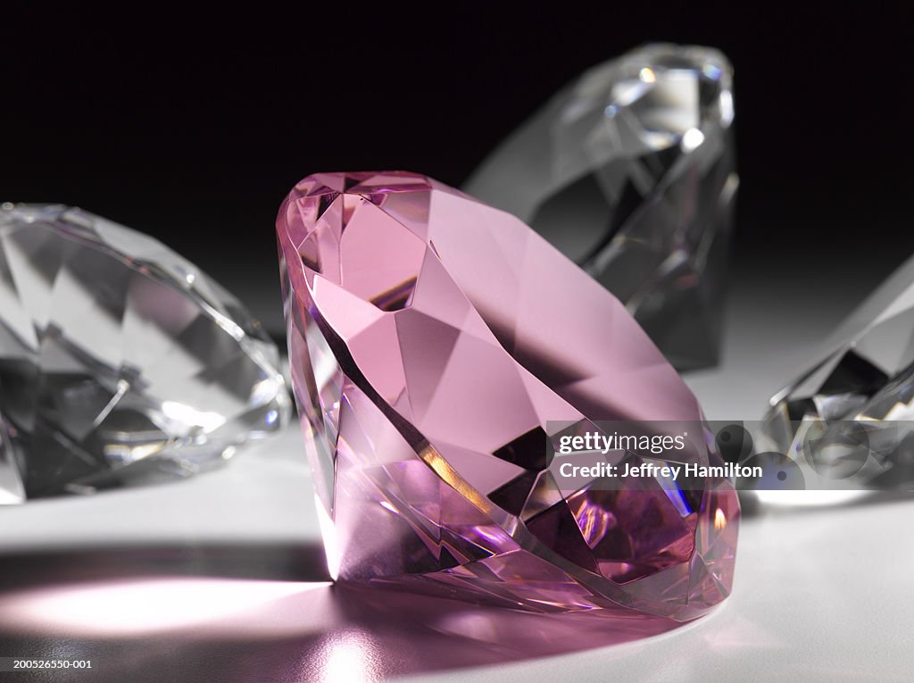 Large pink diamond surrounded by clear diamonds, close-up (still life)