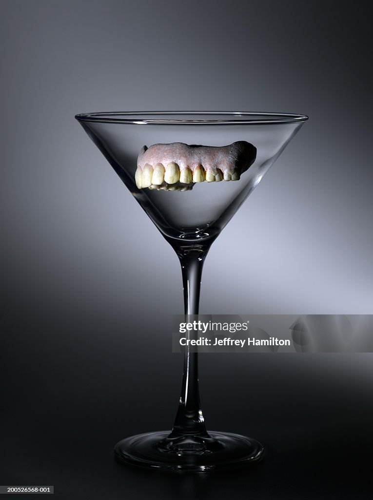 Set of false teeth floating in martini glass (still life)