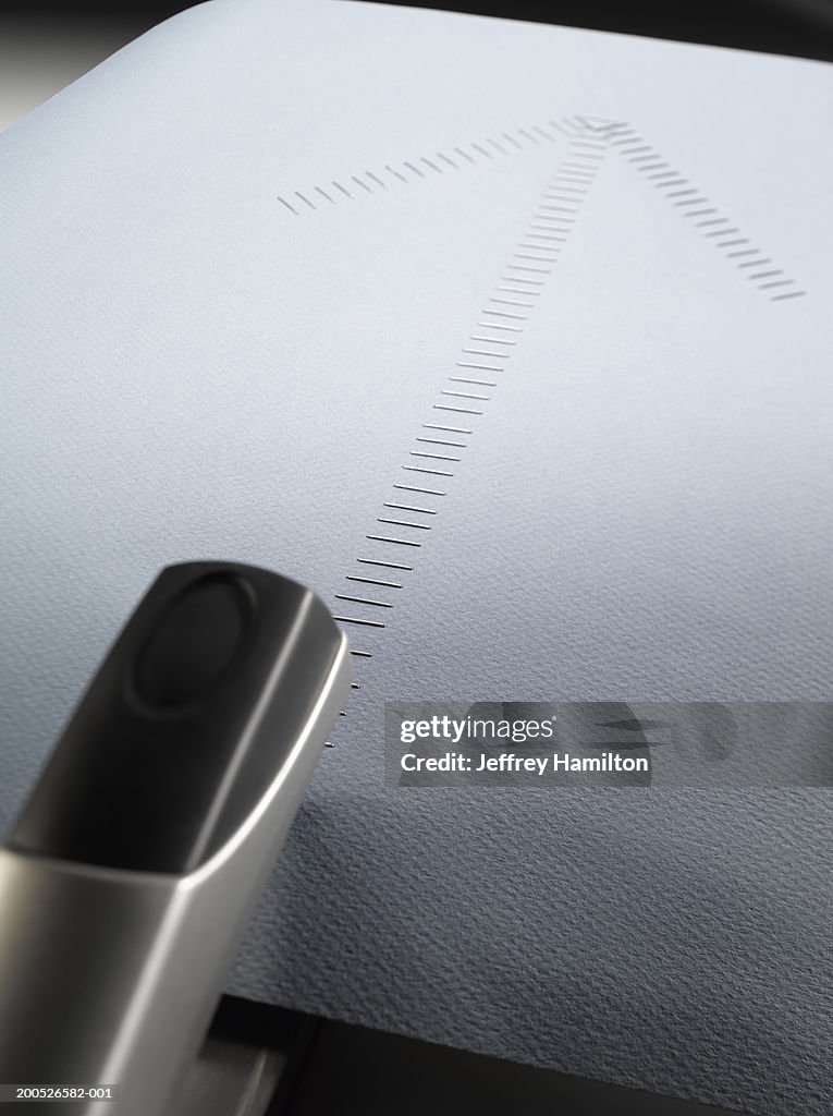 Black stapler beside large group of staples in shape of arrow
