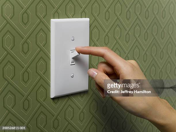 woman turning off light switch on green wallpapered wall, close-up - lichtschalter stock-fotos und bilder