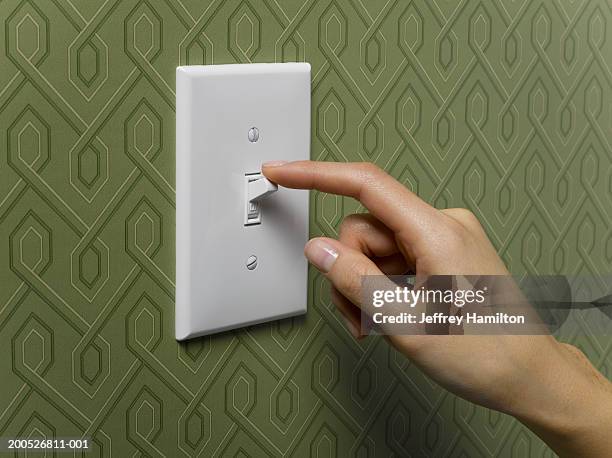 woman turning off light switch on green wallpapered wall, close-up - turning on light switch stock pictures, royalty-free photos & images