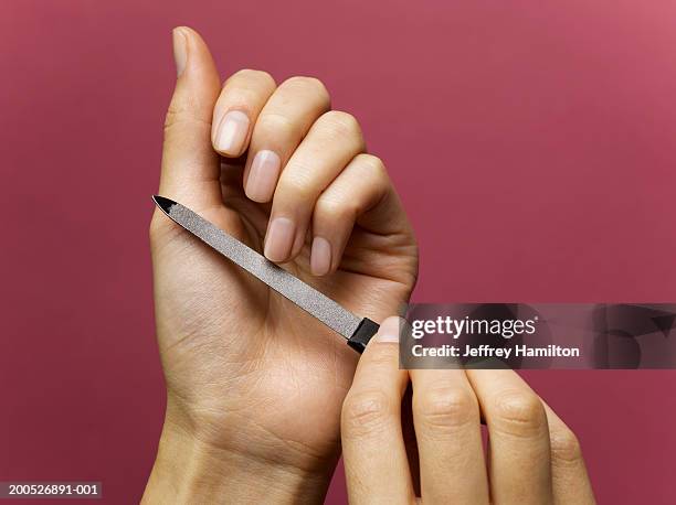 woman filing nails against red background (personal perspective) - filing stock-fotos und bilder