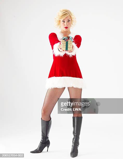 young woman in santa suit giving gift, portrait - nikolausstiefel stock-fotos und bilder