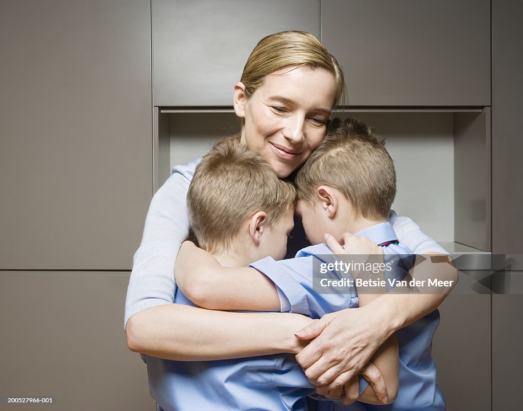 Twin boys (8-10) embracing mother, smiling