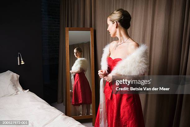 woman in red dress looking in bedroom mirror - evening wear ストックフォトと画像