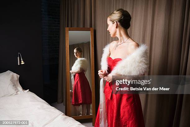 woman in red dress looking in bedroom mirror - woman in evening gown stock pictures, royalty-free photos & images