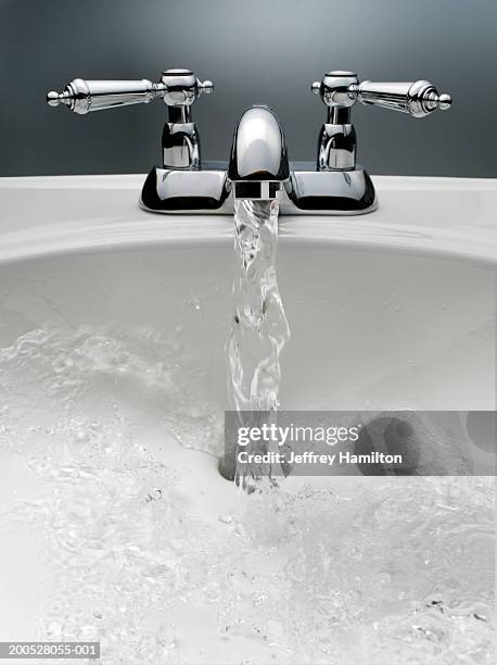 water pouring from sink faucet - grondstoffen stockfoto's en -beelden