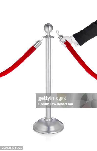 man hooking velvet rope on stanchion, wearing glove - roped off stock illustrations