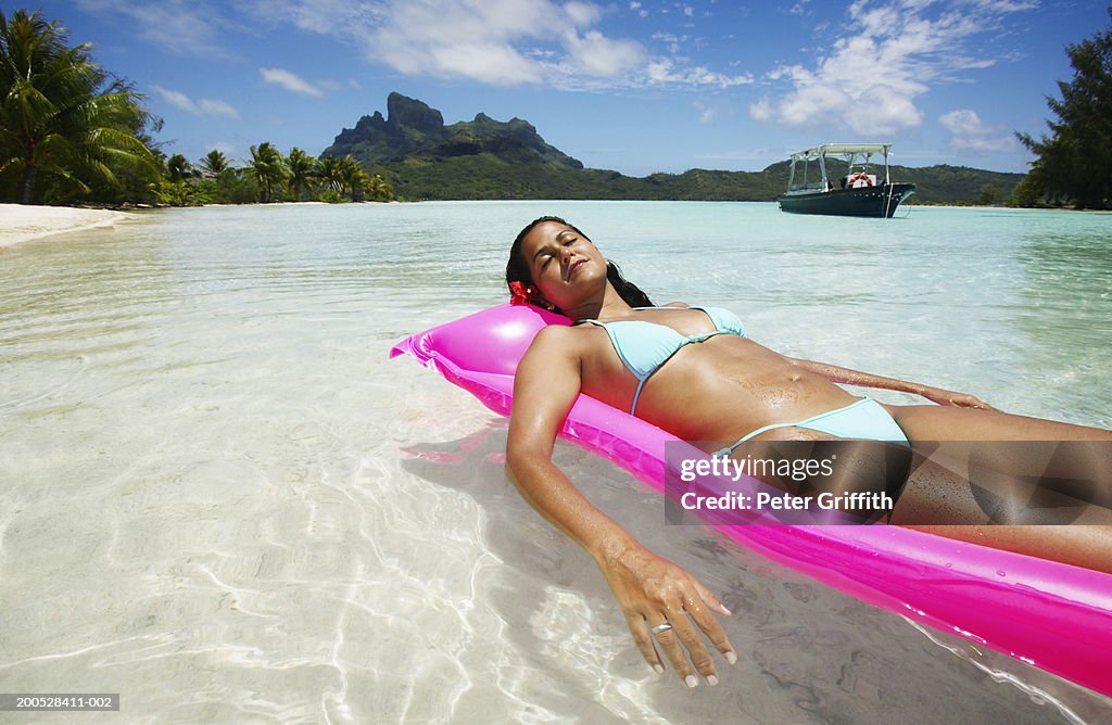 Young woman lying on inflatable in sea, with eyes closed