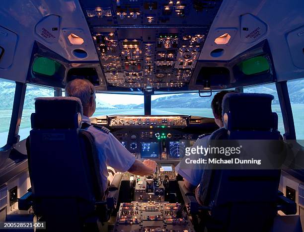 pilots sitting in flight simulator, rear view - pilot fotografías e imágenes de stock