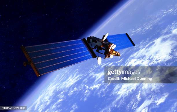 communication satellite over the earth - orbiting foto e immagini stock