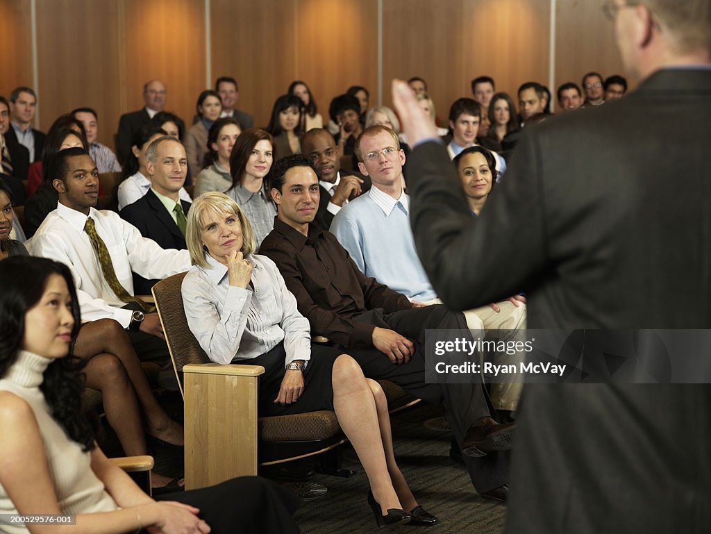 Group of executives listening to man leading seminar in auditorium