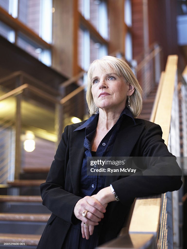 Mature businesswoman standing on stairway, looking away