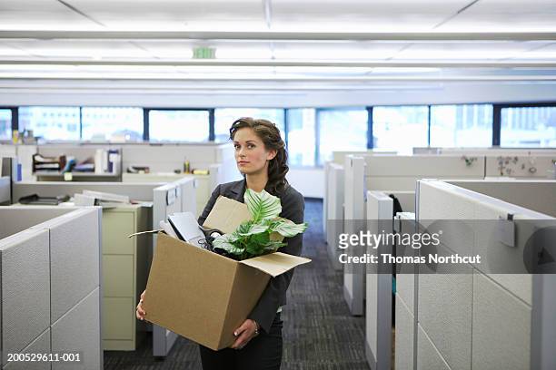 young businesswoman carrying cardboard box in office, portrait - downsizing stock-fotos und bilder