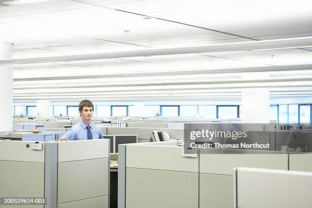 young businessman standing in cubicle, portrait - cubicles imagens e fotografias de stock