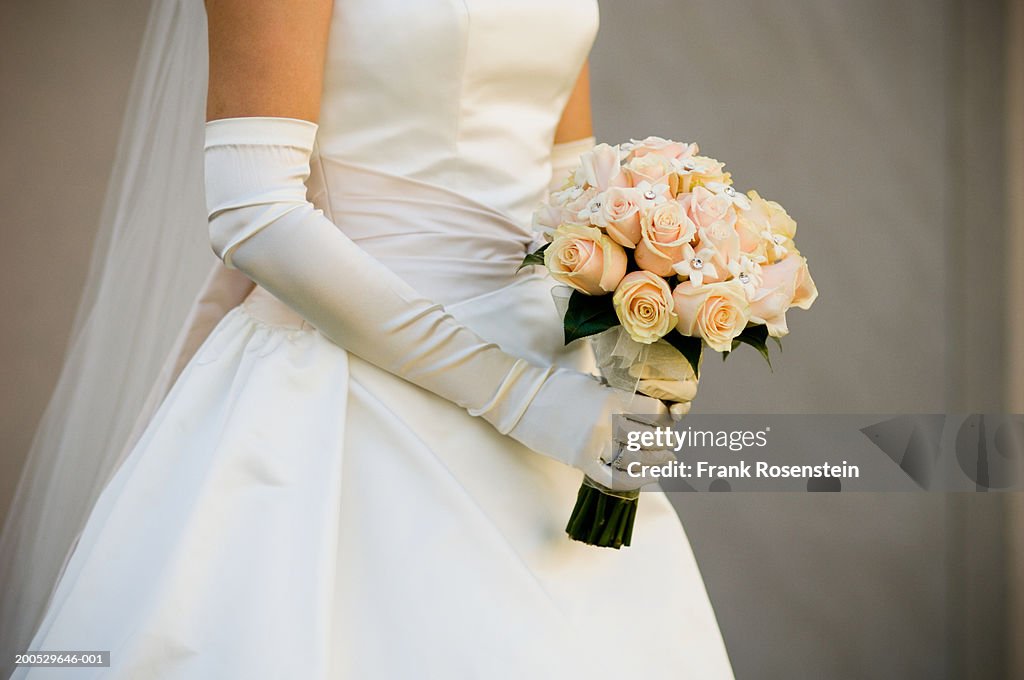 Bride holding bouquet, mid section, side view