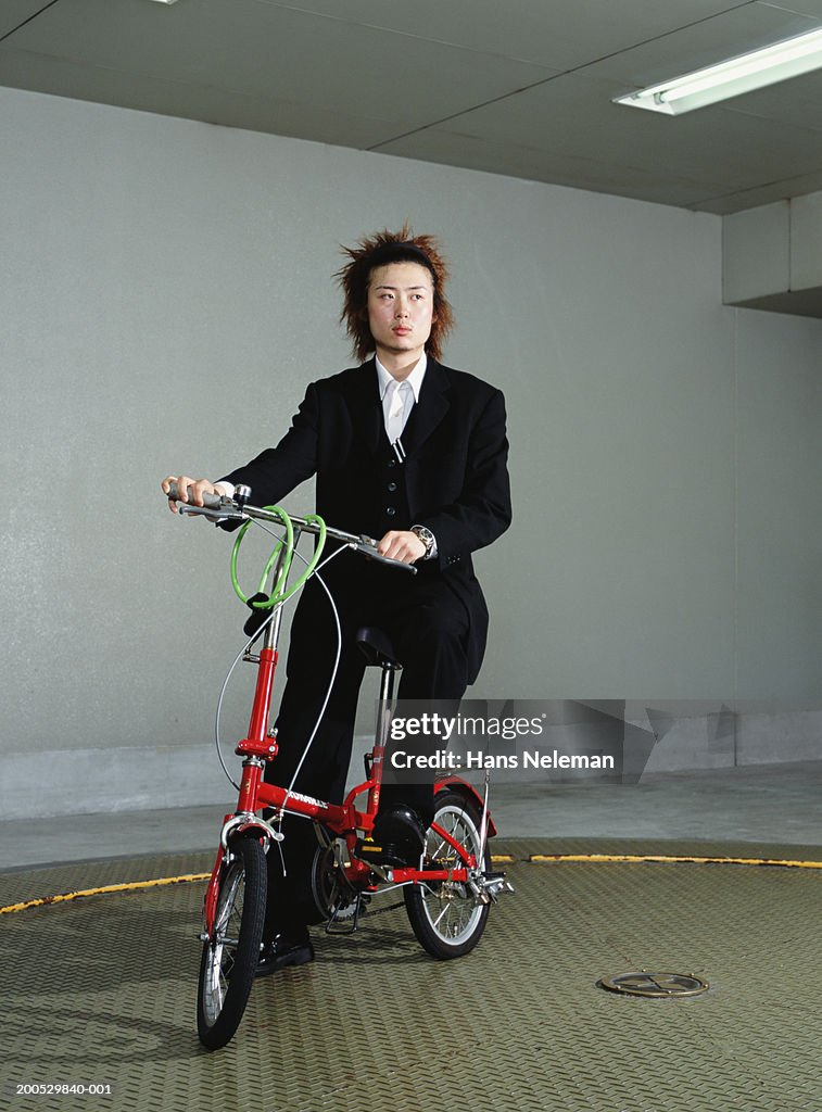 Young businessman on folding bicycle, portrait