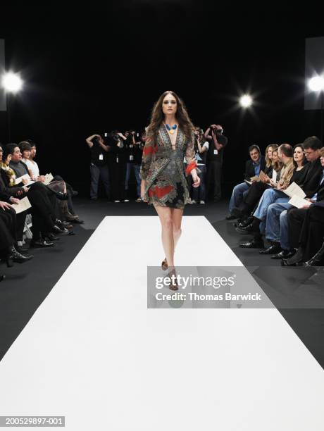 young female model on catwalk, group of photographers in background - catwalk background stock pictures, royalty-free photos & images