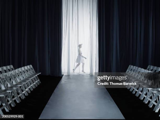 female model (15-17) walking backstage at fashion show, side view - laufsteg stock-fotos und bilder