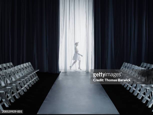 female model (15-17) walking backstage at fashion show, side view - fashion show stockfoto's en -beelden