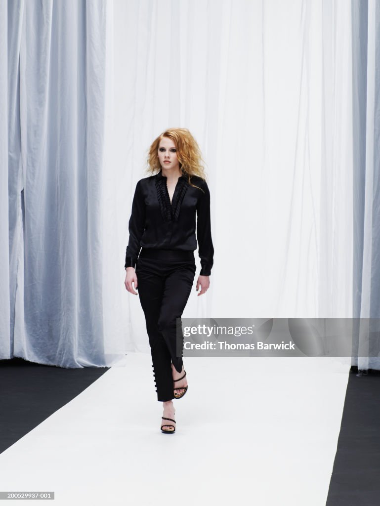 Young female model walking down catwalk
