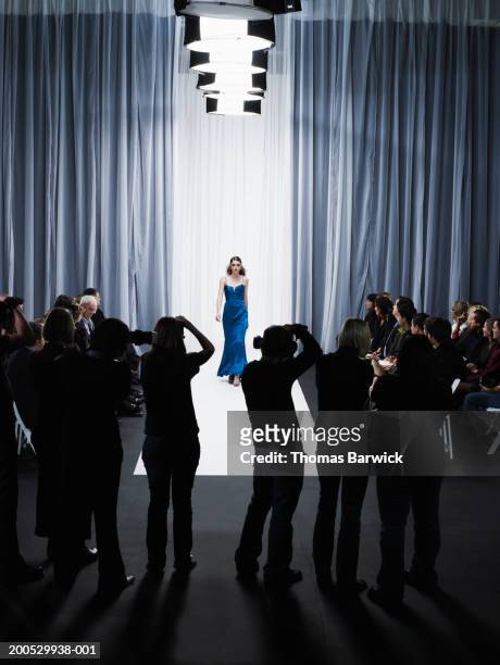 group of photographers in front of female model walking down catwalk - catwalk stock pictures, royalty-free photos & images