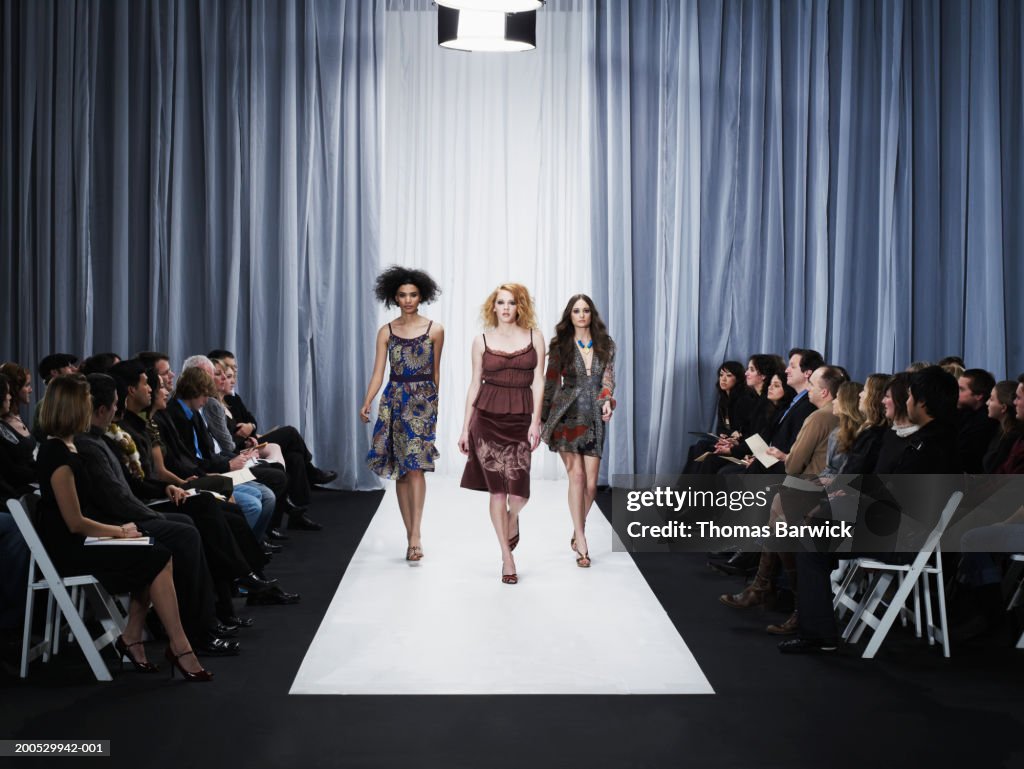 Three female models walking down runway