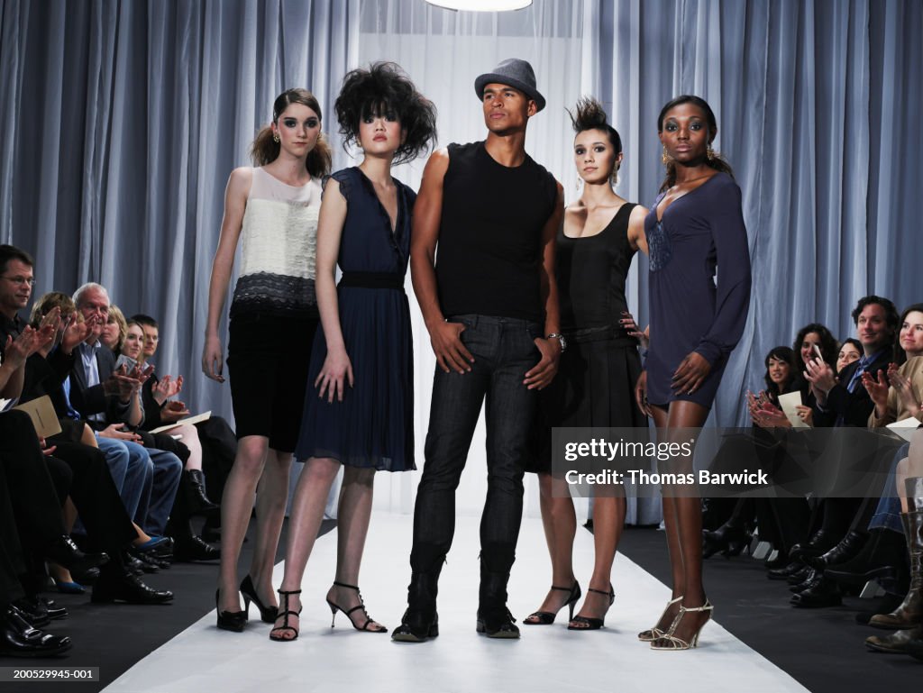 Designer and female models standing on catwalk