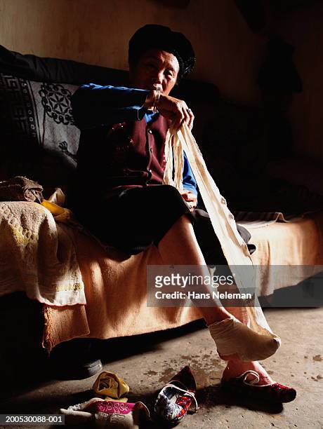 china, senior woman wrapping binding around foot - chinese foot binding stock pictures, royalty-free photos & images