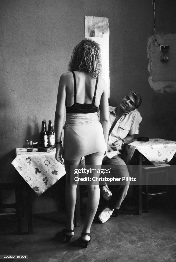 Brazil, Rio de Janeiro, woman standing by man at bar table (B&W)...