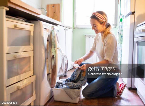 woman finding euro bill while going through the pockets before doing laundry - money laundery stock pictures, royalty-free photos & images