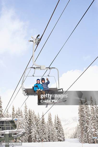 young man and woman on ski lift, low angle view - couple ski lift stockfoto's en -beelden