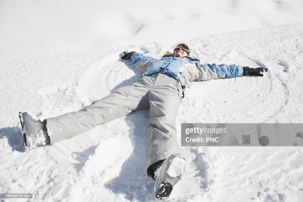 Young woman making snow angel, smiling, elevated view