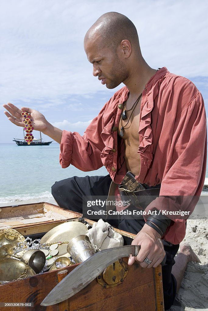 Young man dressed as a pirate looking braclet from treasure chest