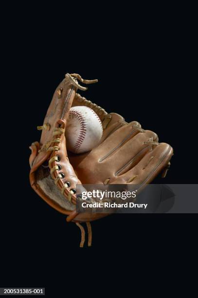 baseball mitt and ball against black background - baseball glove stockfoto's en -beelden