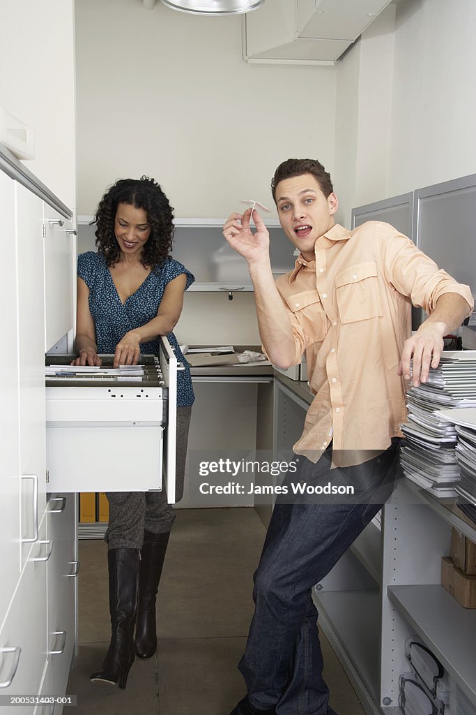 Two male and female office workers in filing room, smiling