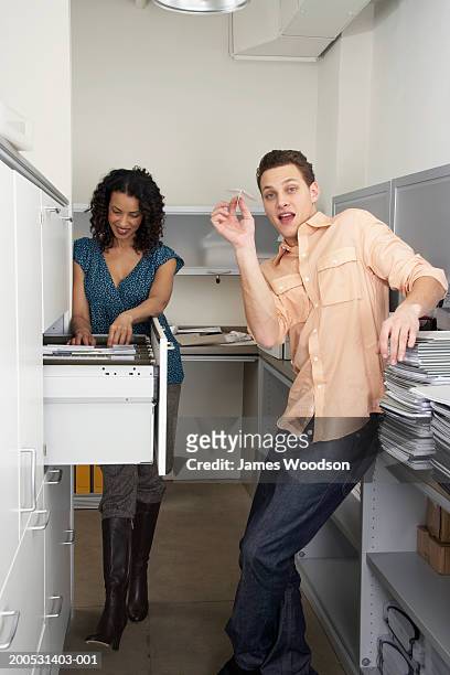 two male and female office workers in filing room, smiling - filing documents stock pictures, royalty-free photos & images