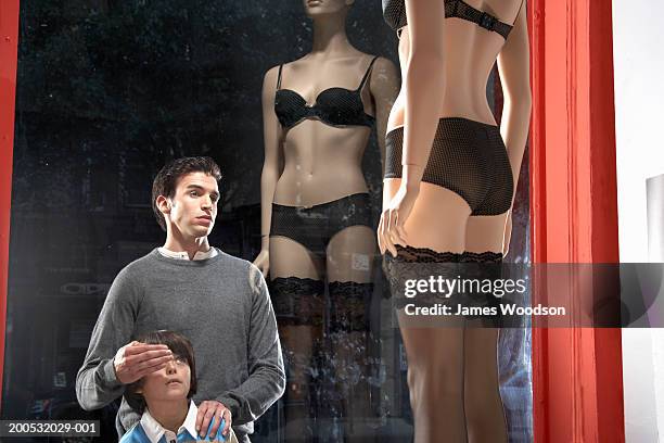 father looking at mannequin in lingerie, covering son's eyes (7-9) - embarrased dad stock pictures, royalty-free photos & images