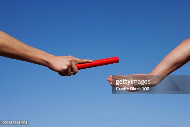 two male runners passing relay baton during race, close-up of hands - stafett bildbanksfoton och bilder