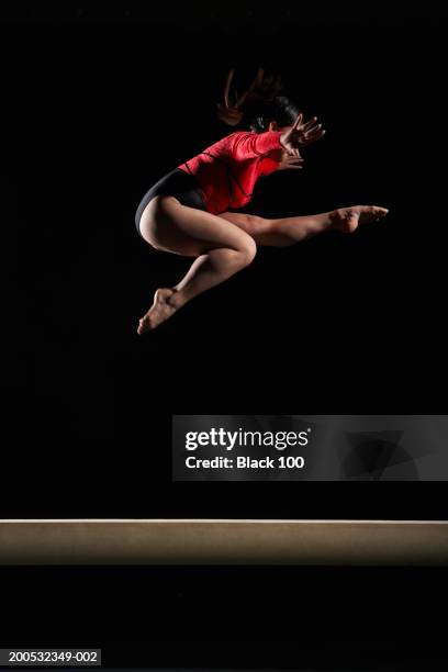 young woman atop balance beam leaping in midair, side view - over 100 stock-fotos und bilder