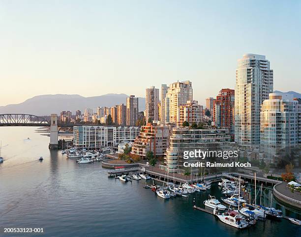 canada, british columbia, vancouver, yachts moored in marina, city skyline in background - vancouver foto e immagini stock