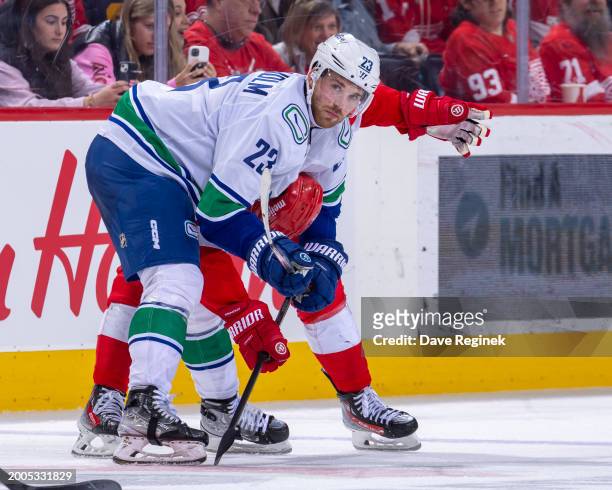 Elias Lindholm of the Vancouver Canucks grabs the head of Lucas Raymond of the Detroit Red Wings on a face off during the third period at Little...