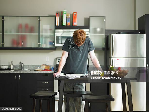 man reading newspaper in domestic kitchen - refrigerator front stock pictures, royalty-free photos & images