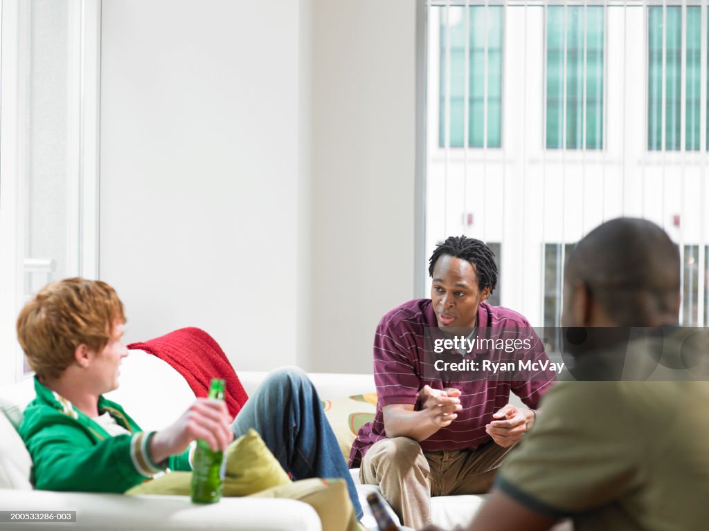 Three men talking and drinking beer in living room