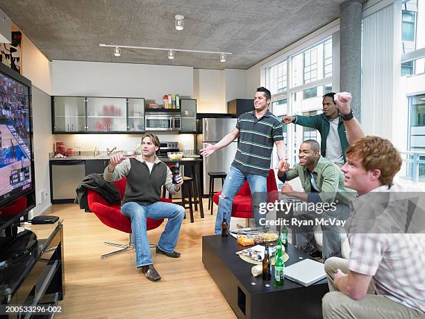 five men watching sports on television, cheering - man cave stock-fotos und bilder