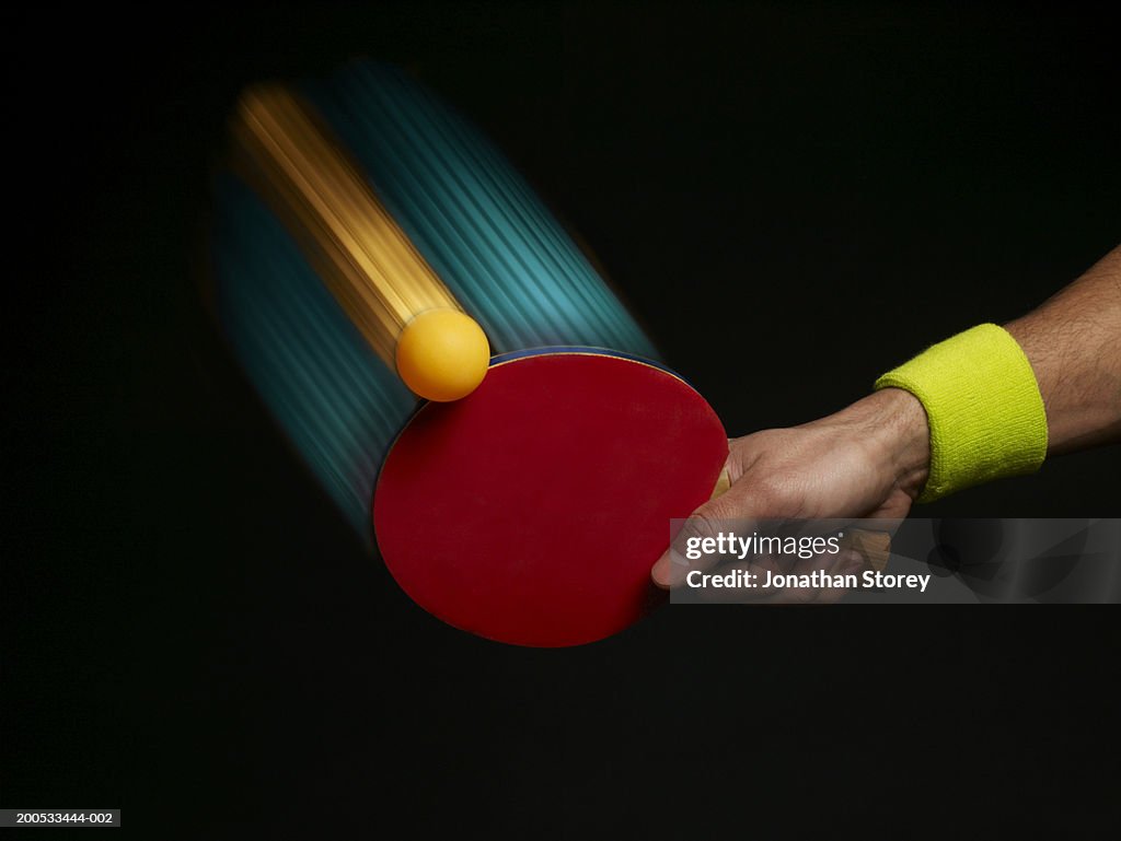 Young man playing table tennis, close-up of hand, (digital composite)