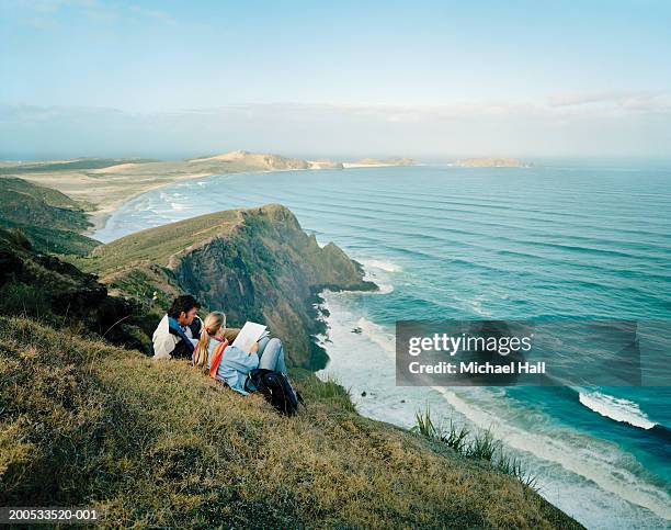 new zealand, cape reinga, couple resting on clifftop - région du northland photos et images de collection