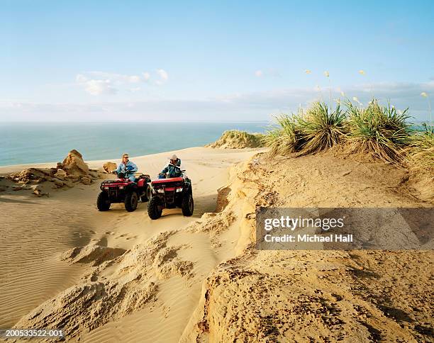 new zealand, ninety mile beach, couple quadbiking - région du northland photos et images de collection