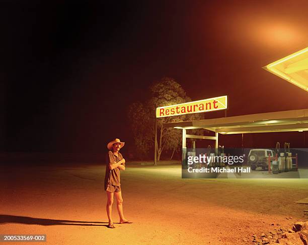 man standing on forecourt of petrol station illuminated at night - petrol forecourt stock pictures, royalty-free photos & images